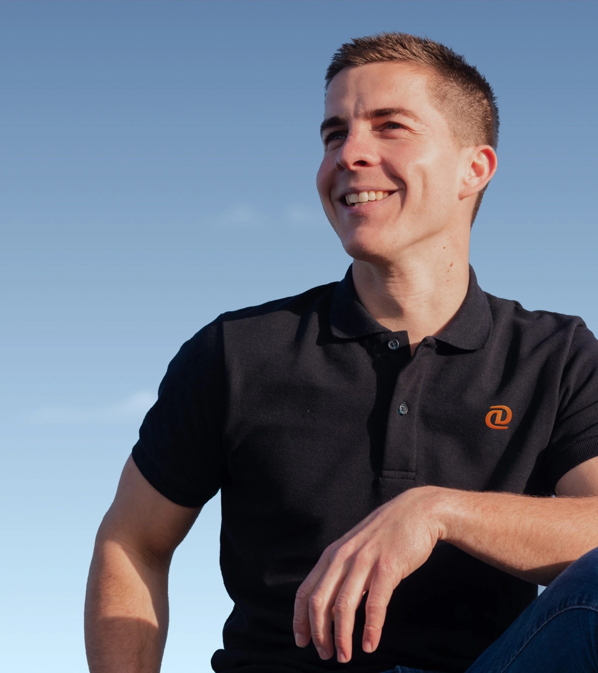 Black polo shirt embroidered with the orange DataDocks symbol