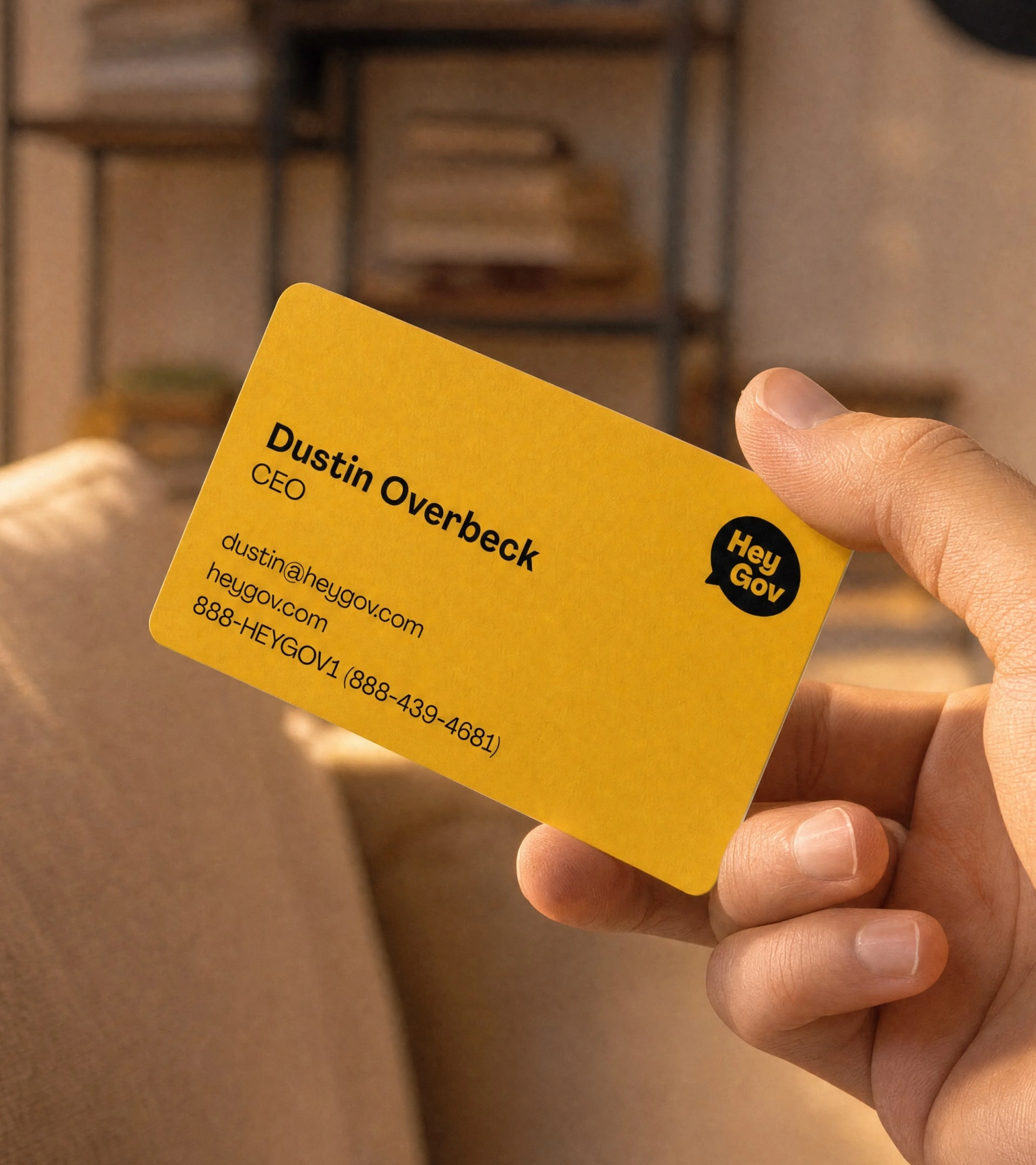 Yellow HeyGov business card held in one hand